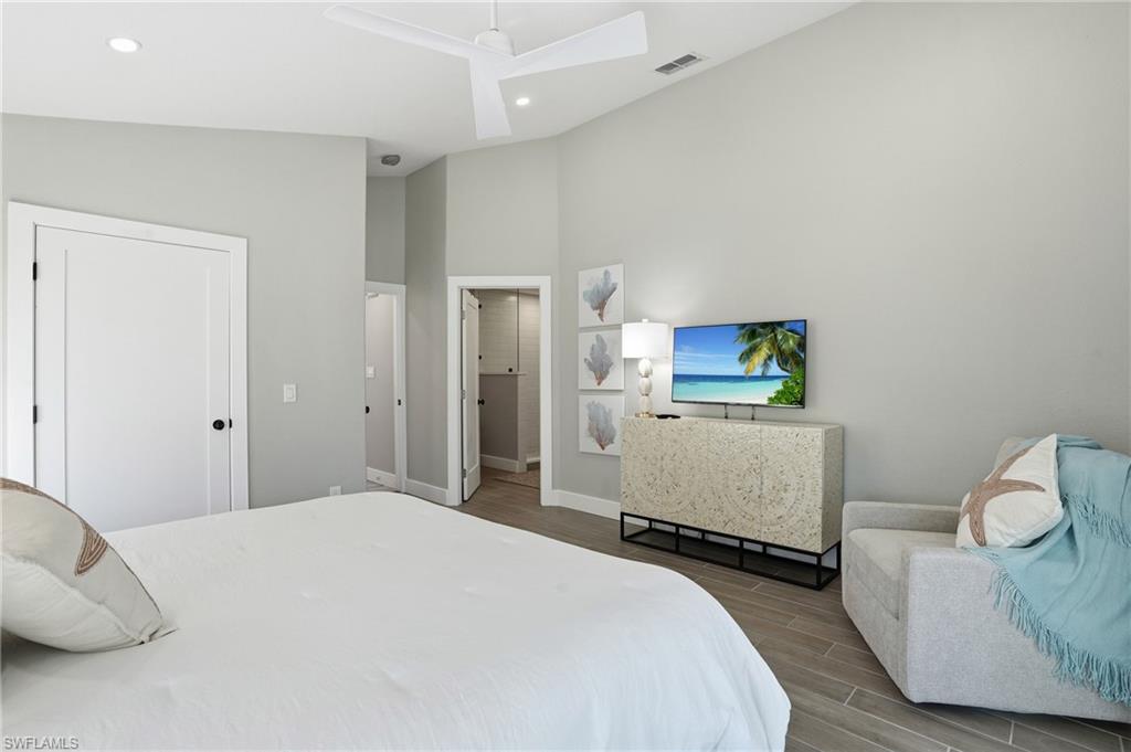 Bedroom featuring wood finish floors, a high ceiling, a ceiling fan, a closet, and recessed lighting - Virtually Edited Image