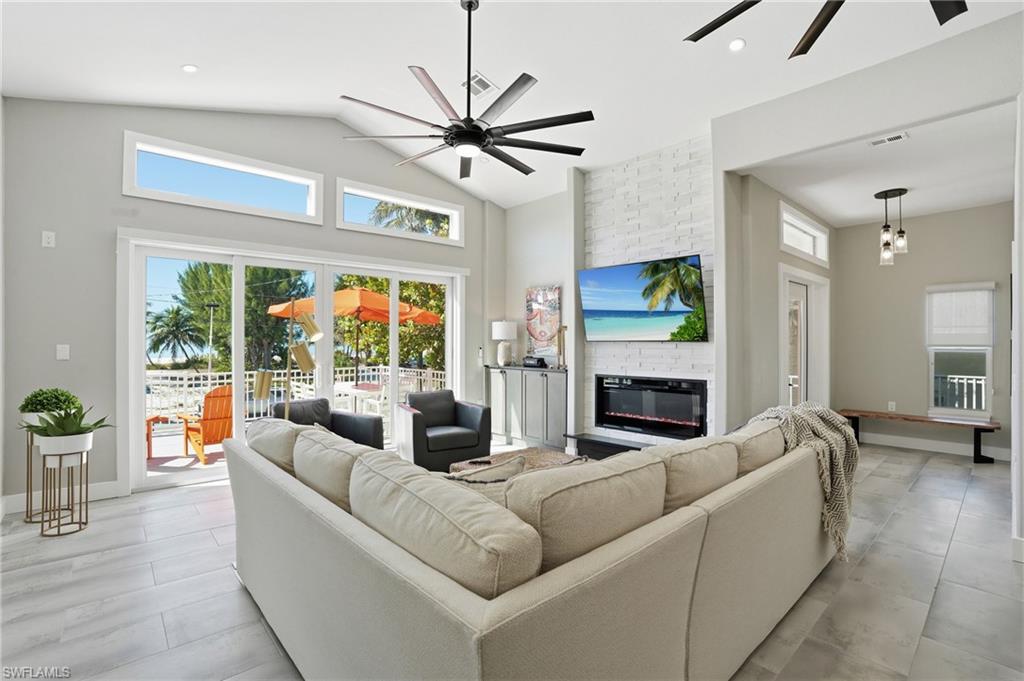 Living area with a ceiling fan, a large fireplace, vaulted ceiling, and recessed lighting - Virtually Edited Image
