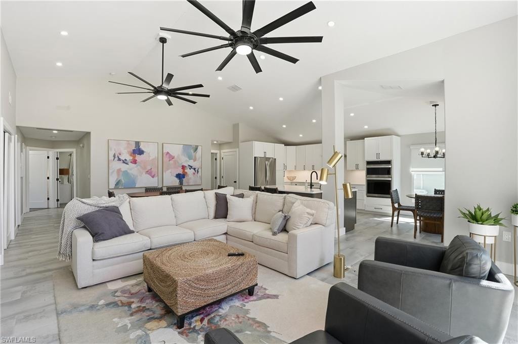 Living area featuring a ceiling fan, hanging lights, and vaulted ceiling - Virtually Edited Image