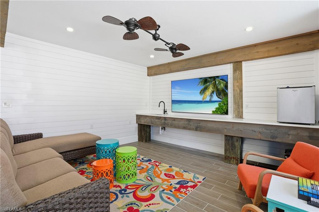 Living room with wood finish floors, ceiling fan, wood walls, and recessed lighting - Virtually Edited Image
