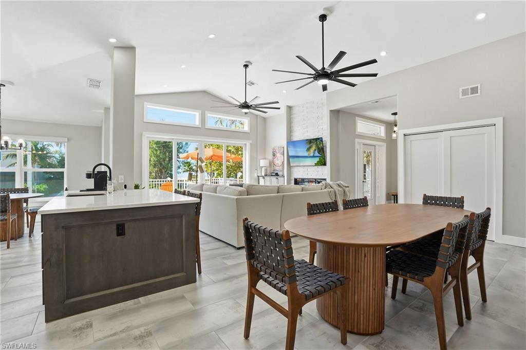 Dining area featuring healthy amount of natural light, lofted ceiling, a ceiling fan, a chandelier, and a fireplace - Virtually Edited Image