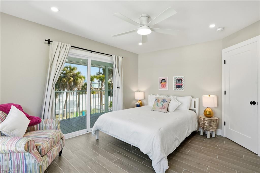 Bedroom with wood finish floors, access to exterior, recessed lighting, and a ceiling fan - Virtually Edited Image