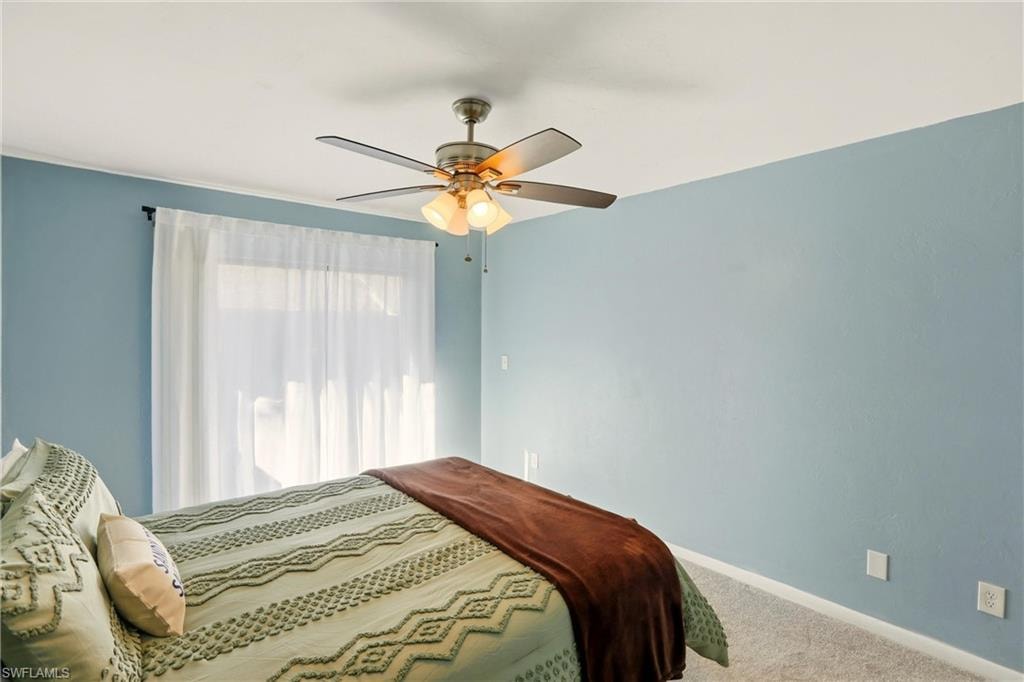 Carpeted bedroom featuring baseboards and ceiling fan