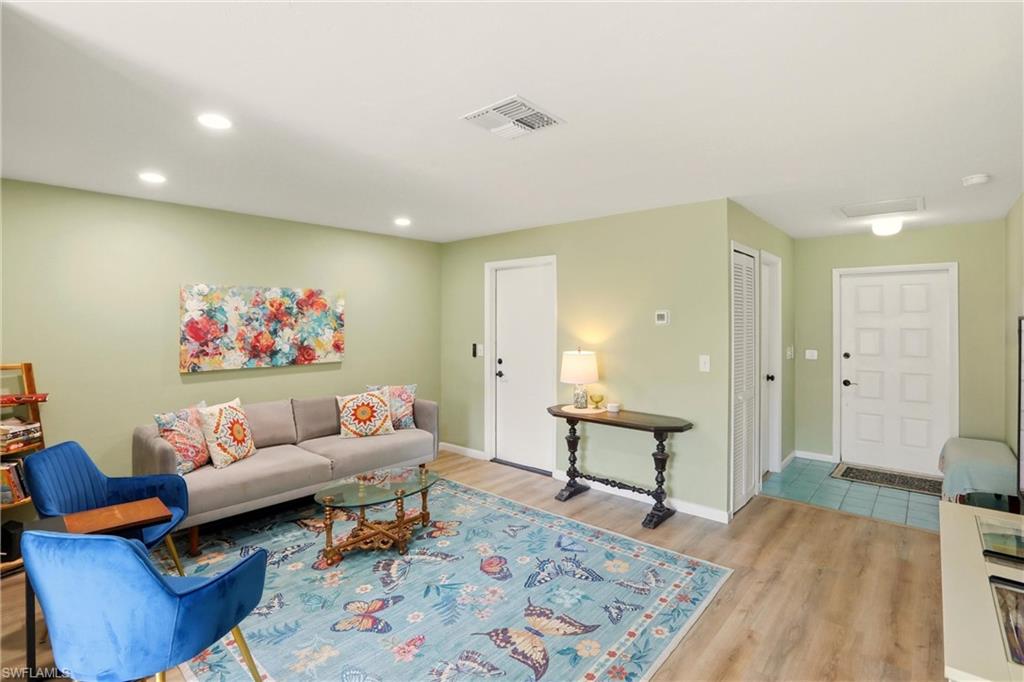 Living room with light wood-type flooring and recessed lighting