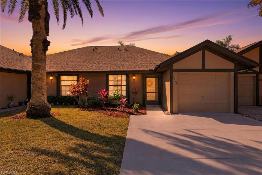View of front of home with driveway, a lawn, and roof with shingles
