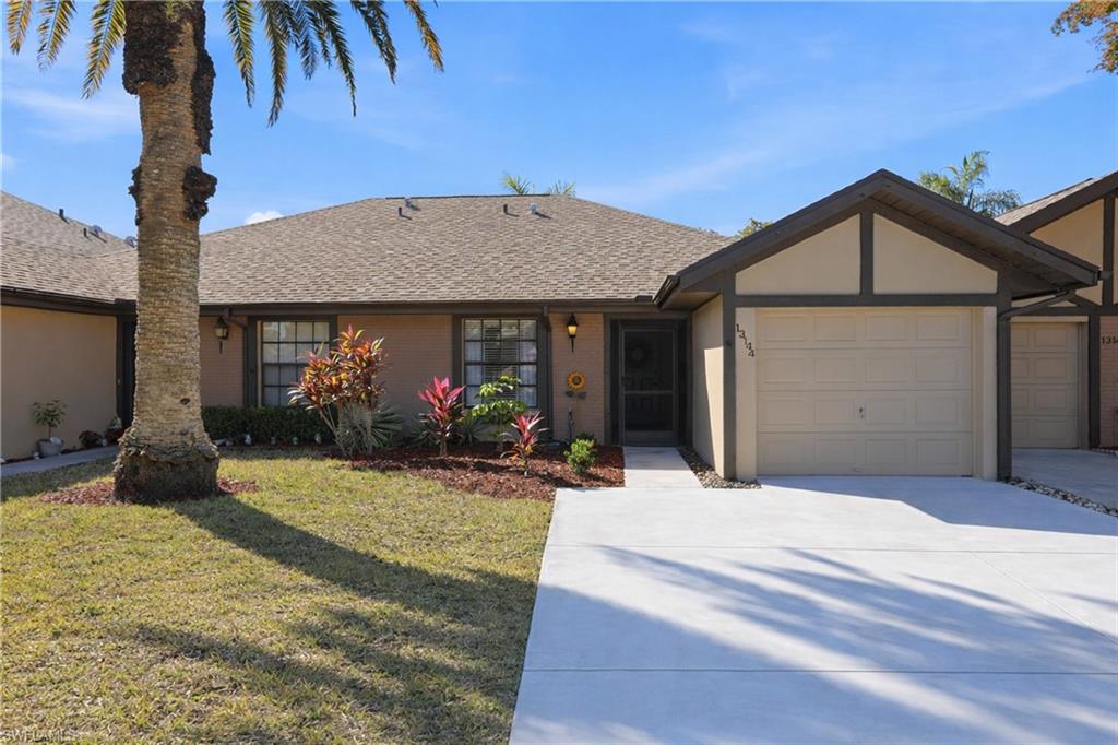 Single story home with a front yard, driveway, a shingled roof, and stucco siding