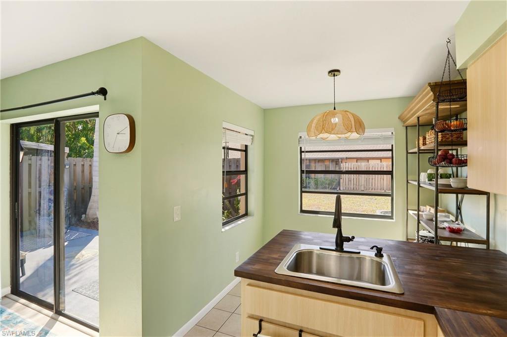 Kitchen featuring light wood finish cabinetry, decorative light fixtures, light tile patterned floors, open shelves, and butcher block countertops