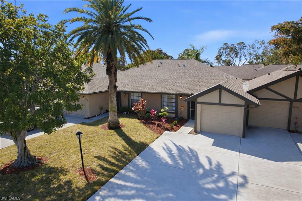 Ranch-style home featuring an attached garage, roof with shingles, driveway, stucco siding, and a front yard