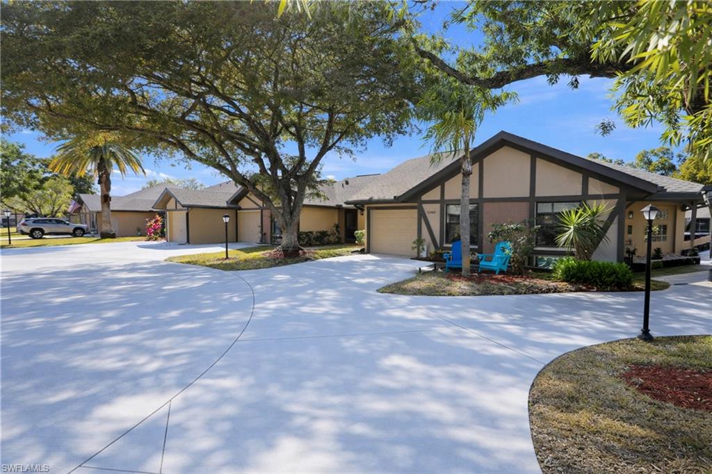 View of front facade with stucco siding, curved driveway, and an attached garage