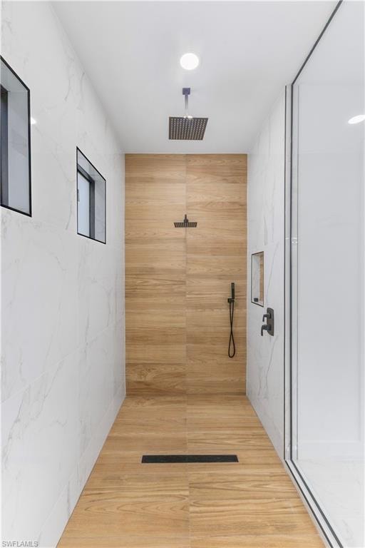 Bathroom featuring a marble finish shower and tile walls