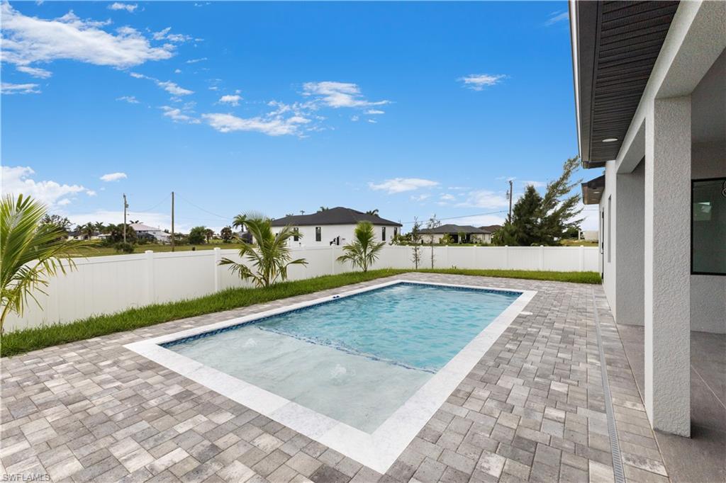 View of swimming pool featuring patio surround and a fenced backyard