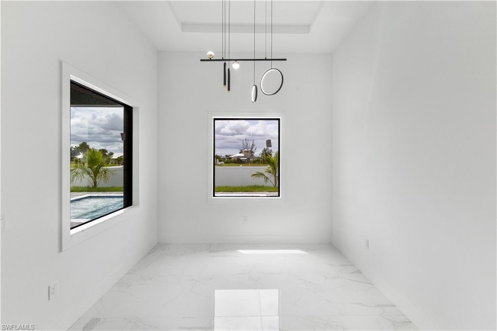 Unfurnished dining area featuring light marble finish floors and baseboards