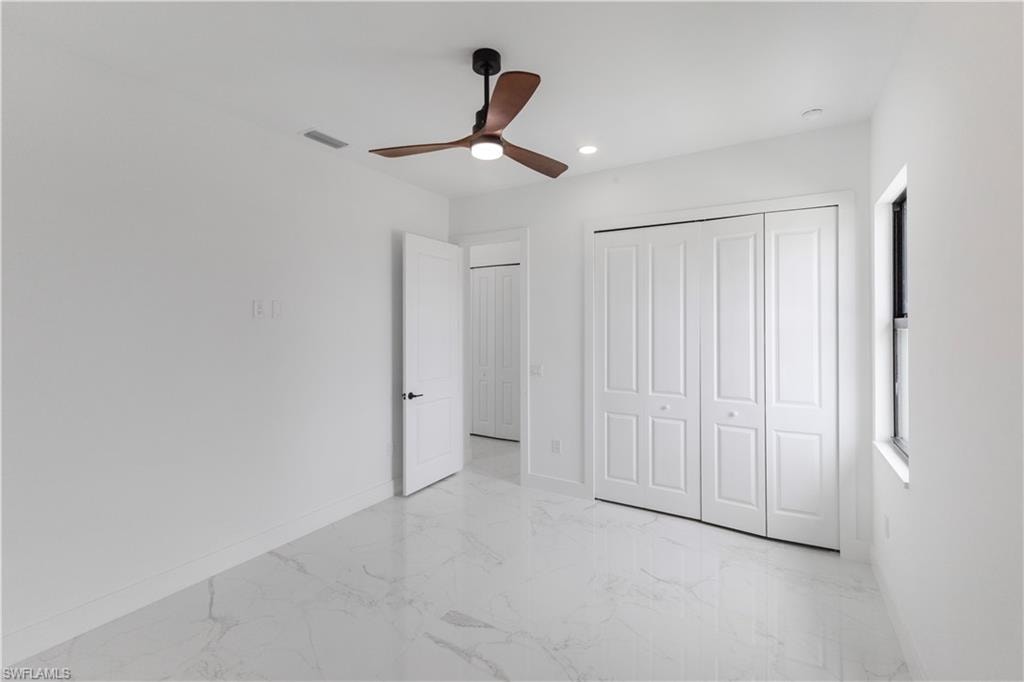 Unfurnished bedroom with light marble finish floors, a closet, a ceiling fan, and recessed lighting