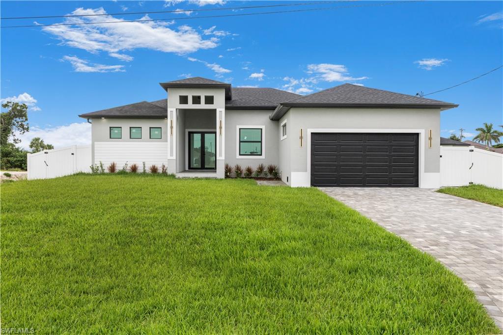 Prairie-style house with a gate, decorative driveway, an attached garage, and stucco siding