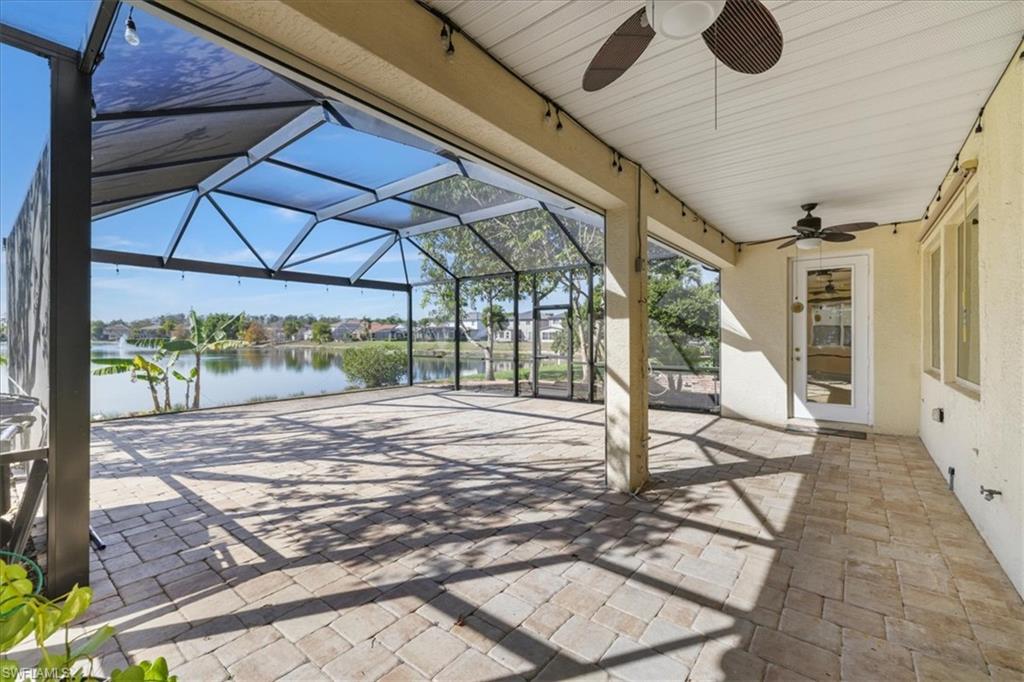 View of patio / terrace featuring a lanai, a sunroom, ceiling fan, a water view, and a residential view