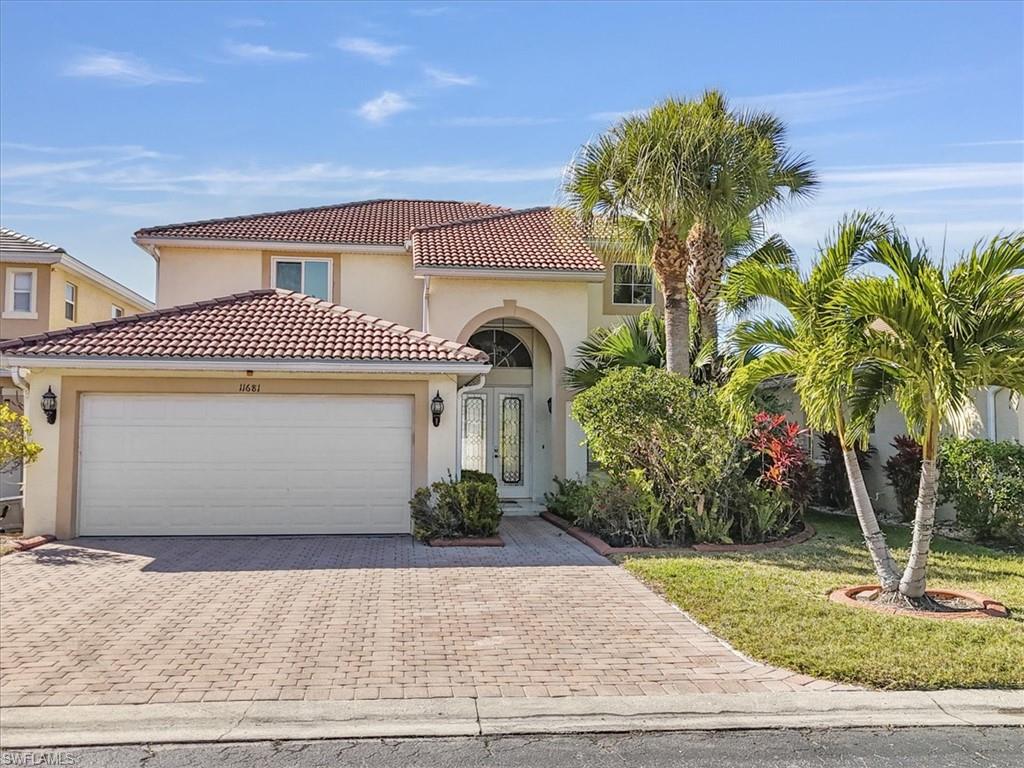 Mediterranean / spanish-style home with stucco siding, driveway, an attached garage, a tile roof, and a front yard