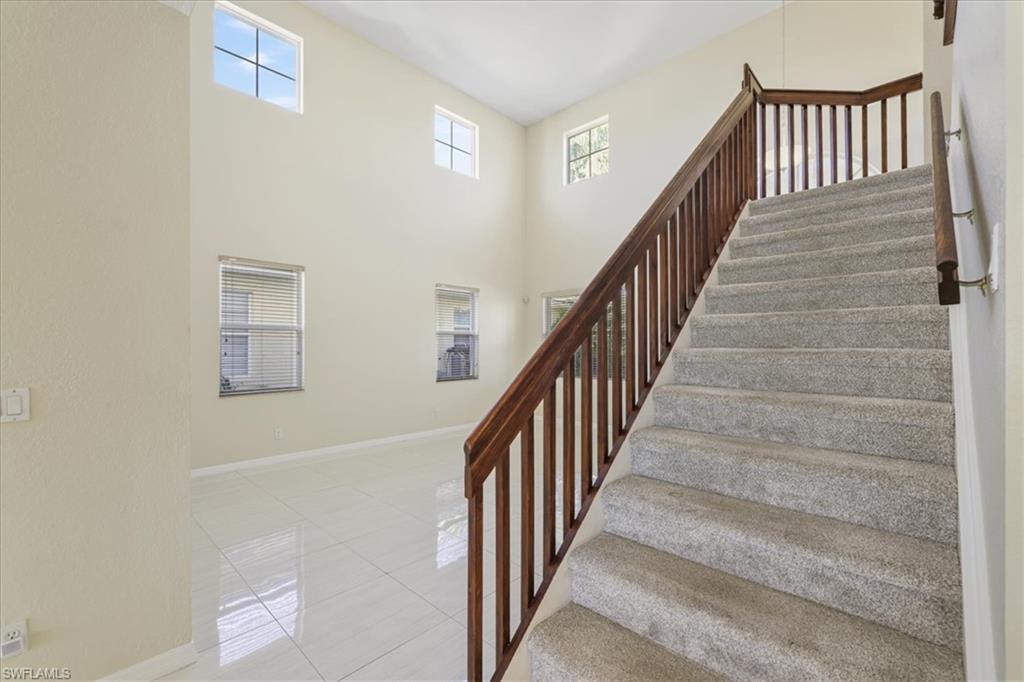 Stairs featuring tile patterned floors, healthy amount of natural light, and a high ceiling