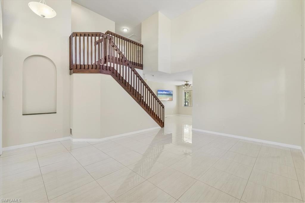 Stairs featuring a high ceiling, a ceiling fan, and tile patterned flooring
