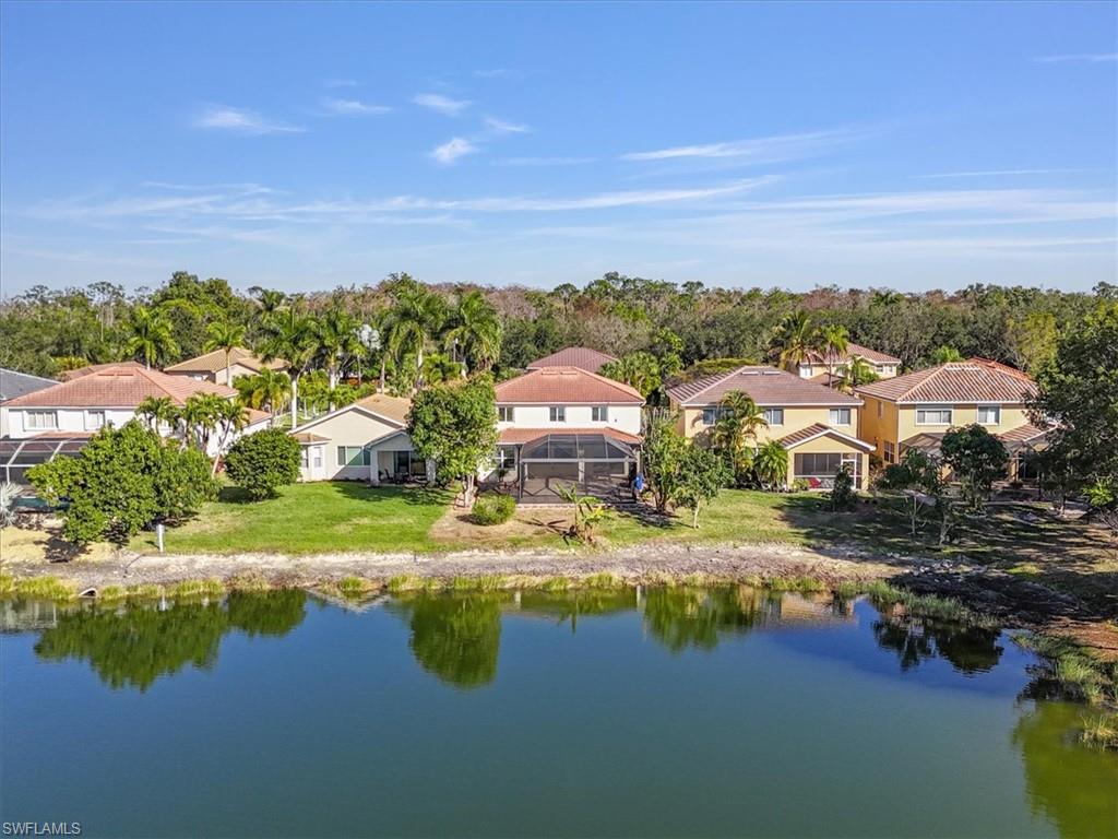 Aerial view of residential area featuring a nearby body of water and a tree filled landscape