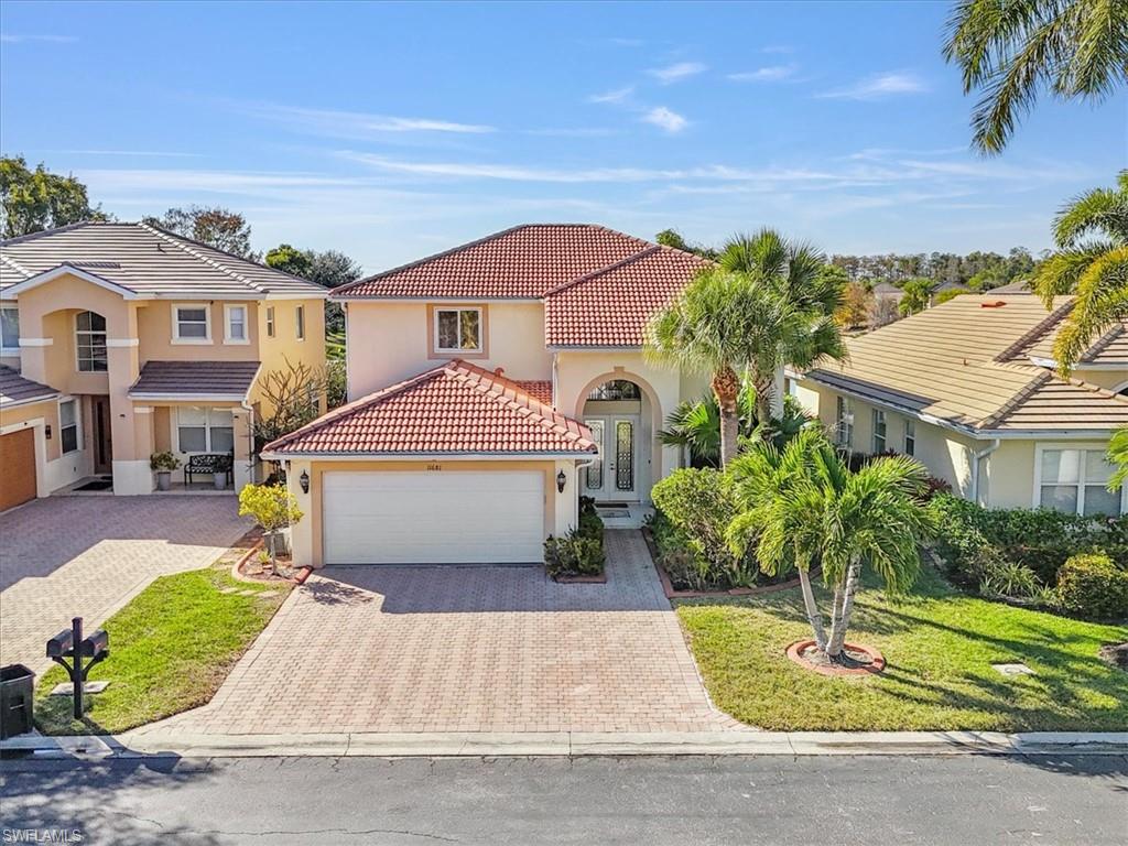 Mediterranean / spanish house featuring stucco siding, decorative driveway, a tile roof, an attached garage, and a front yard