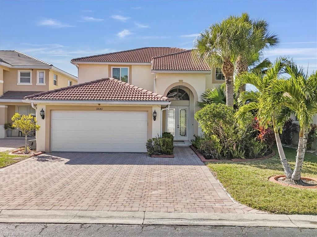 Mediterranean / spanish house with stucco siding, decorative driveway, and an attached garage