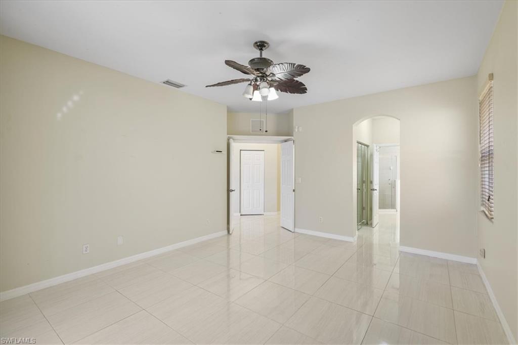 Unfurnished room featuring arched walkways, ceiling fan, and light tile patterned floors