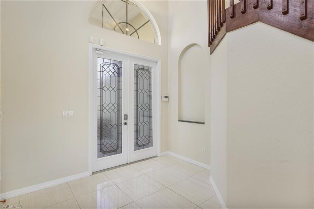 Entryway featuring french doors, light tile patterned flooring, and a high ceiling