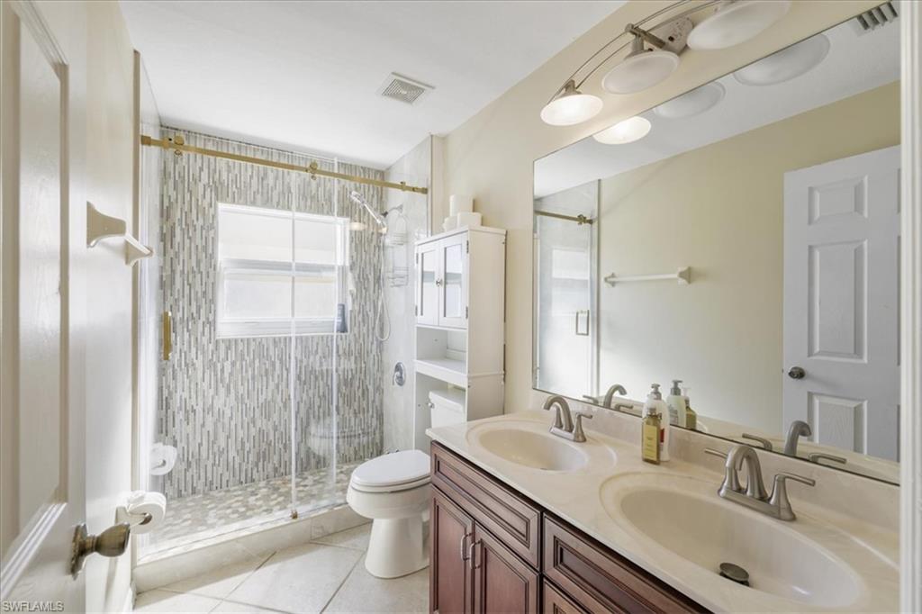 Bathroom with double vanity, a stall shower, and light tile patterned flooring
