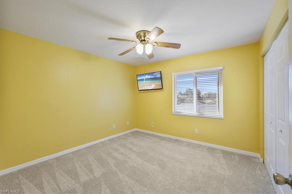Unfurnished bedroom with carpet, a closet, and a ceiling fan