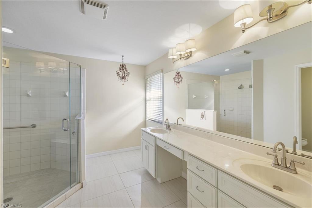 Bathroom featuring a stall shower, double vanity, light tile patterned floors, and recessed lighting