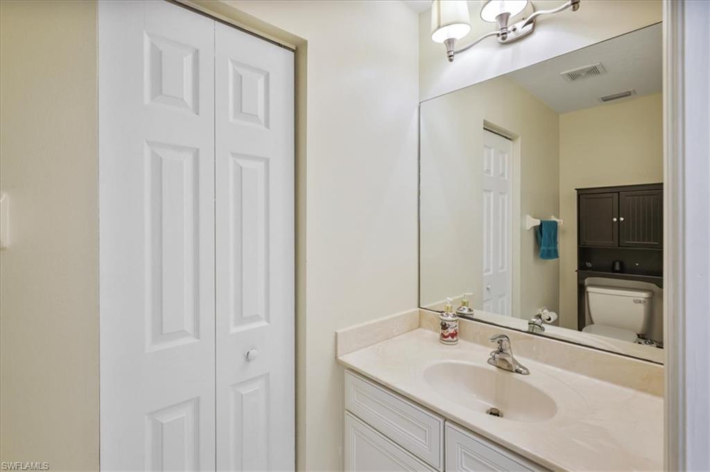 Bathroom with a closet, vanity, and suspended lighting