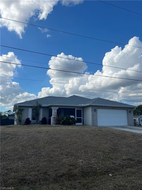 Ranch-style house with a garage, stucco siding, driveway, and a front yard