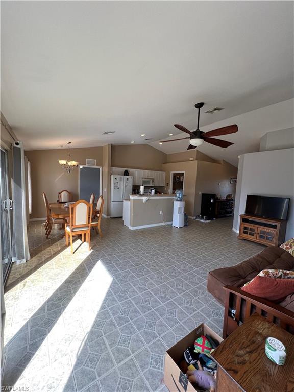 Living area featuring vaulted ceiling, hanging lights, and a ceiling fan