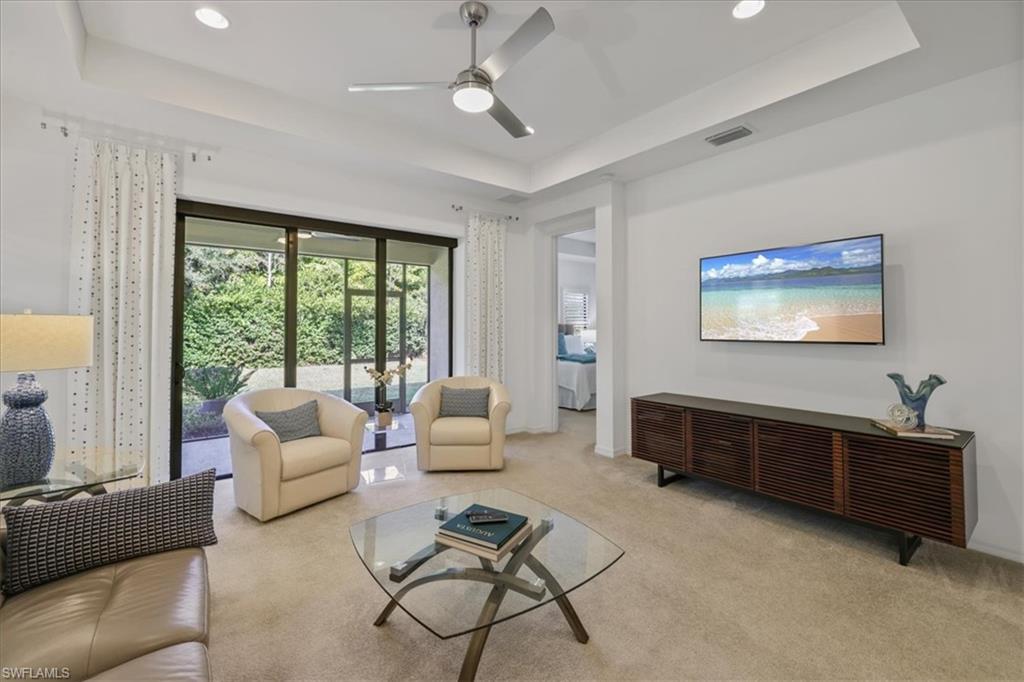 Living area featuring a raised ceiling, ceiling fan, carpet, and recessed lighting