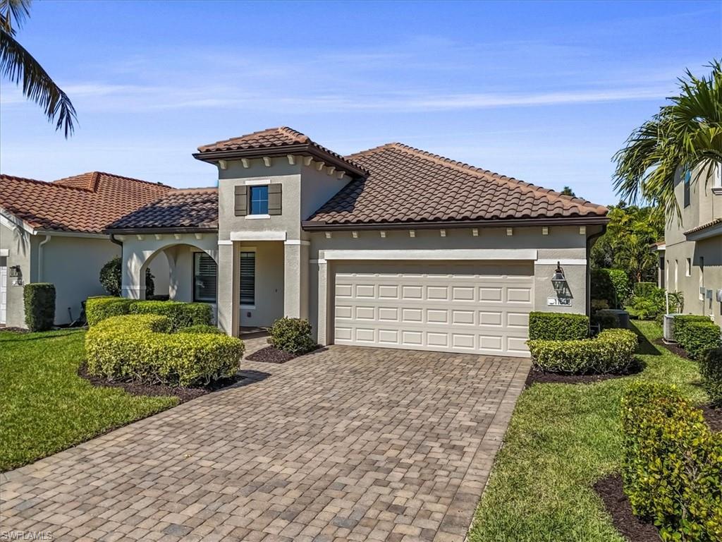 Mediterranean / spanish house with stucco siding, driveway, a garage, a front lawn, and a tile roof