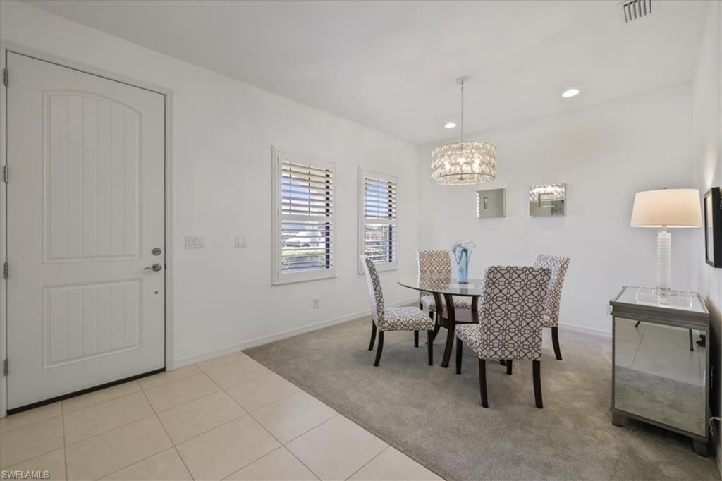 Dining room featuring light tile patterned flooring, hanging lights, and light carpet