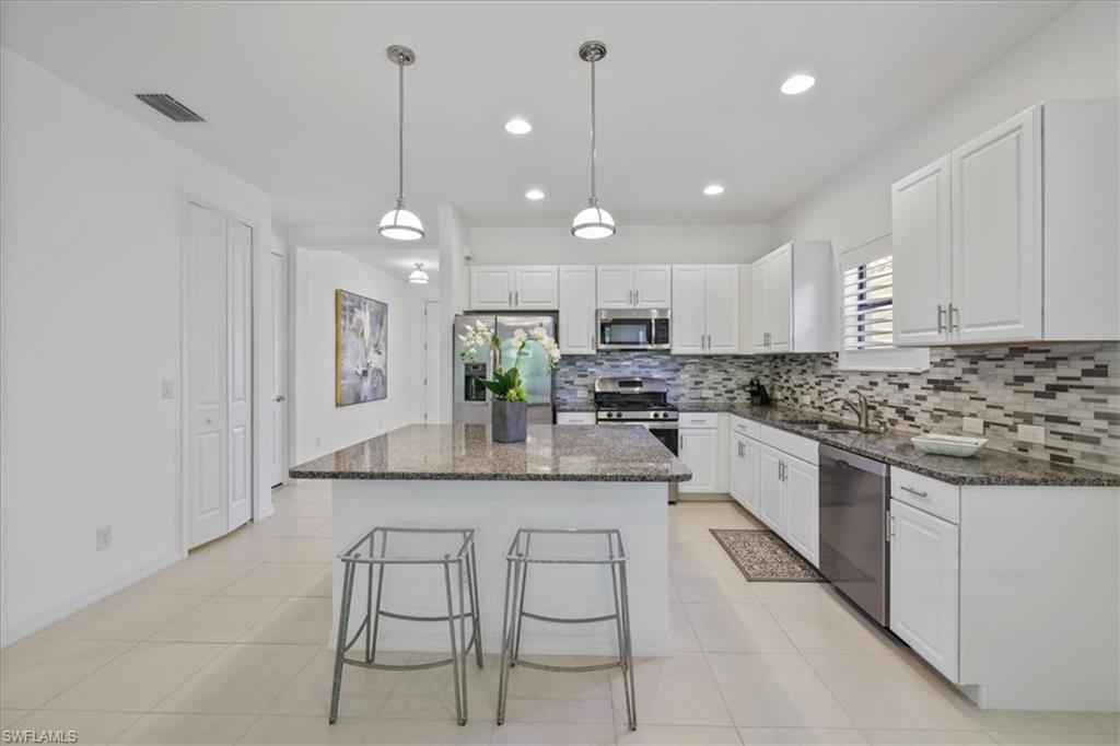 Kitchen with dark stone countertops, stainless steel appliances, and white cabinets