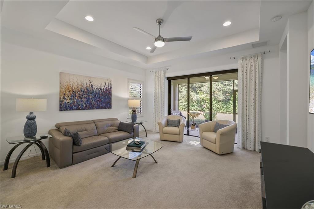 Carpeted living area featuring ceiling fan, a tray ceiling, and recessed lighting