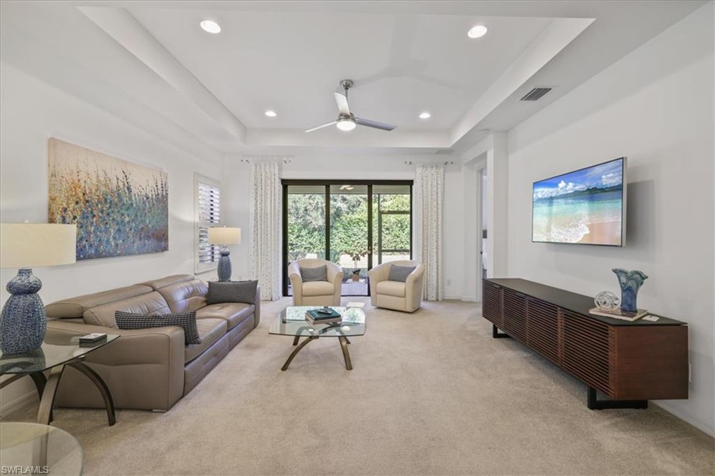 Living room with a tray ceiling, light carpet, a ceiling fan, and recessed lighting