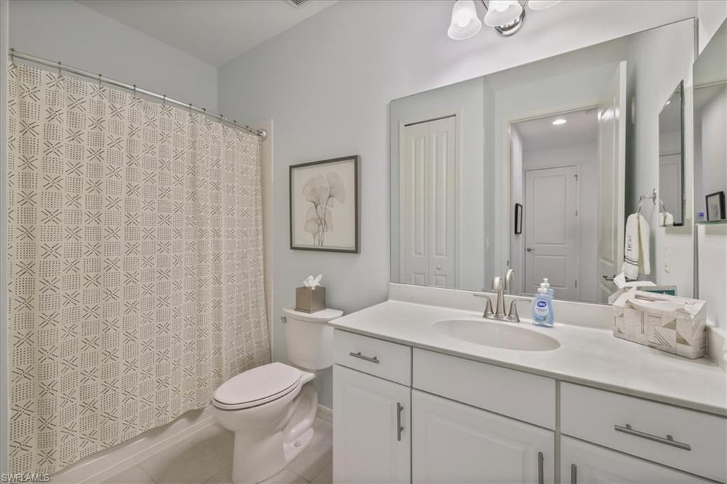 Full bathroom with vanity, shower / tub combo, and light tile patterned floors