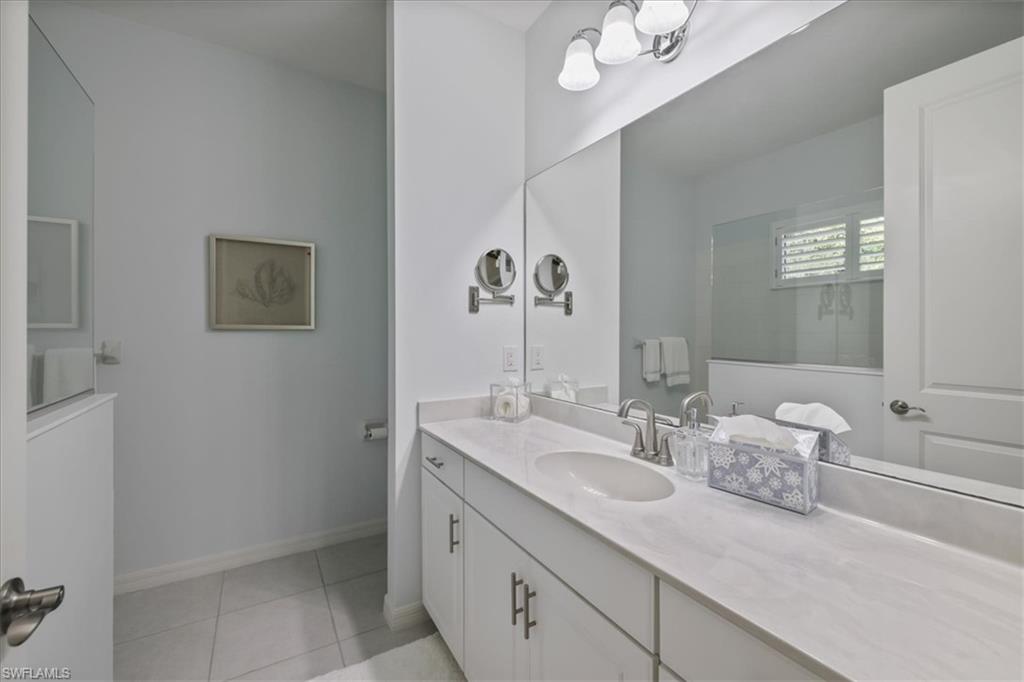 Full bath with vanity, light tile patterned flooring, and suspended lighting