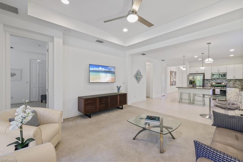 Living room featuring a ceiling fan, recessed lighting, light carpet, and light tile patterned floors