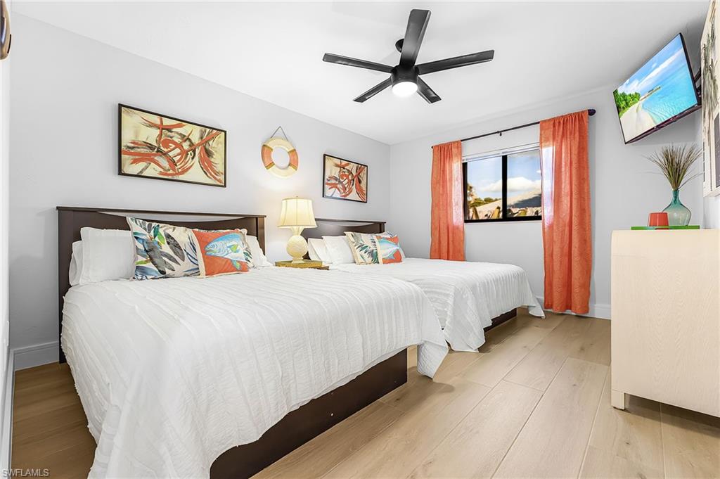 Bedroom featuring 2 Queen beds, double window overlooking lush flower garden, TV and a ceiling fan