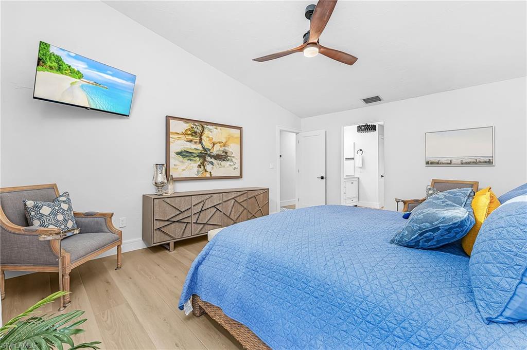 Primary Bedroom featuring a King size bed, ceiling fan, TV, sitting area, and ensuite bathroom