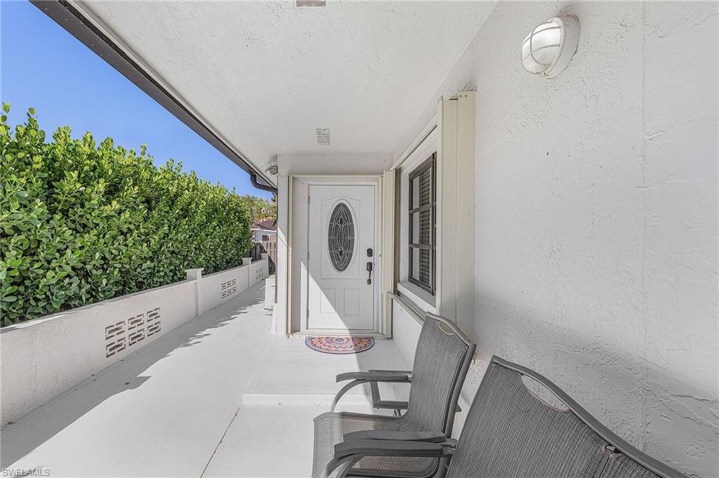 Covered porch entrance to property featuring a double glider, and 2 chairs to enjoy beautiful sunsets