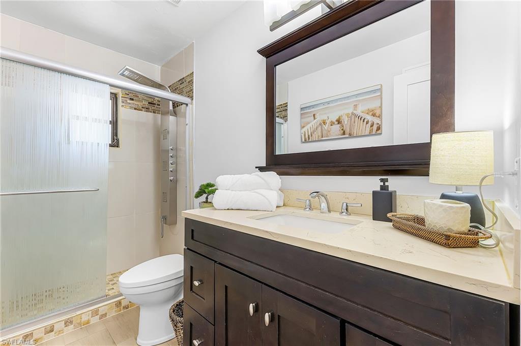 Bathroom featuring granite countertop vanity and a walk-in tile shower with body spray