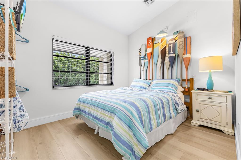 Nautical vaulted bedroom featuring a Queen bed, double window overlooking covered entry porch, TV, ceiling fan and ample open closet hanging concept