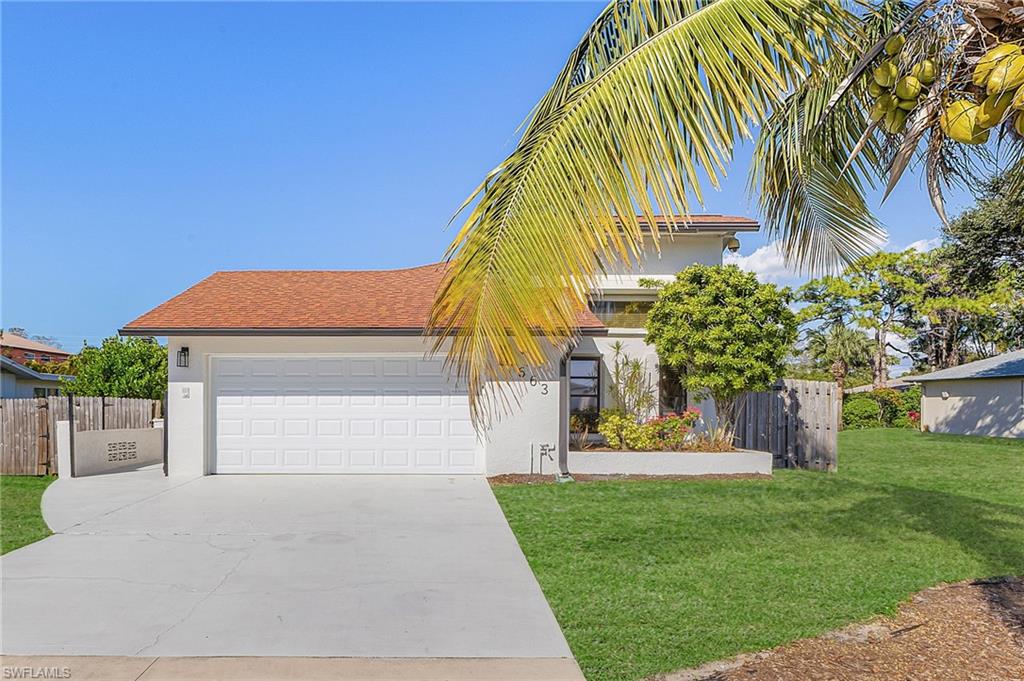 View of front of house with concrete driveway driveway, stucco siding, an attached 2 car garage and coconut tree