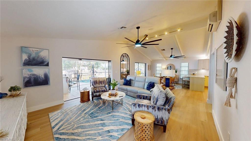 Living area featuring vaulted ceiling, light wood-type flooring, healthy amount of natural light, and large ceiling fans