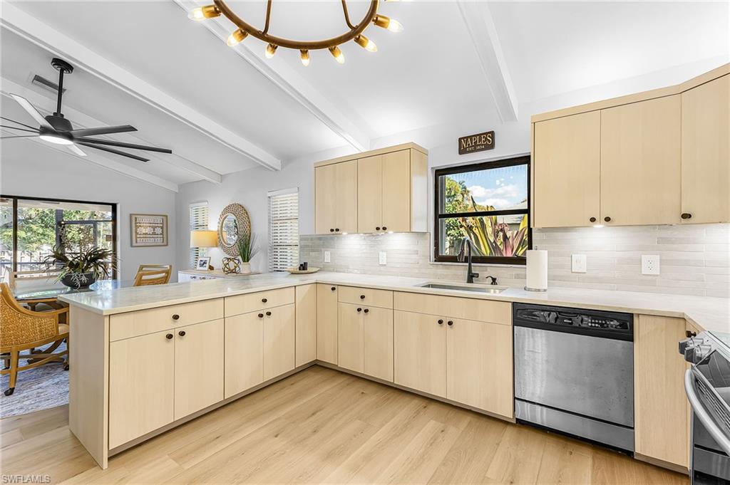 Kitchen with a peninsula bar, stainless steel appliances, light wood-type flooring, light wood finish modern cabinetry, and vaulted ceiling with beams